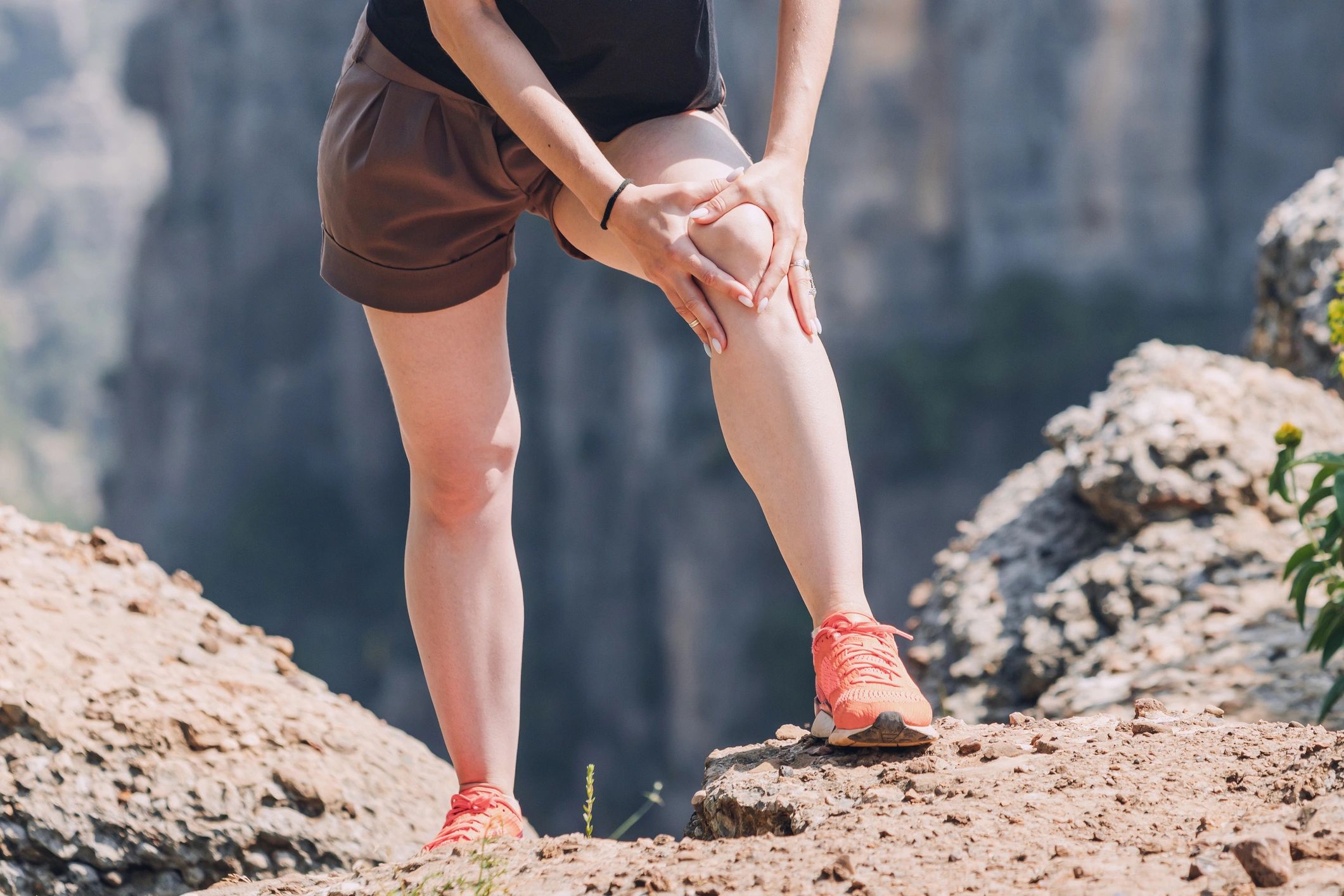 Lady with swelling in her legs stops to massage knee while on hike - if she had compression, no pain