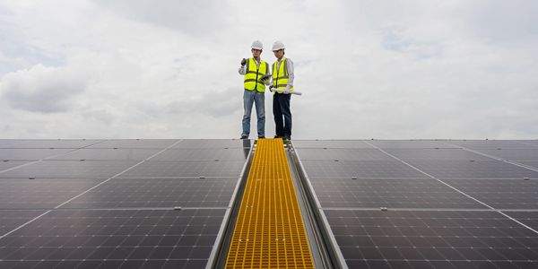 Group pf people smiling and looking at a solar panel project