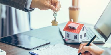 Person handing over house keys with contract signing.