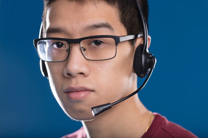 Asian thoughtful and serious adult with headset, typical of gamers or call centers, waiting ready to help. Teamwork is key in both fields