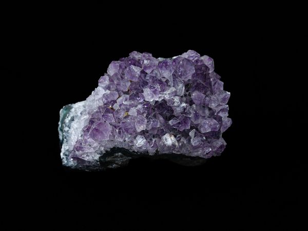 A cluster of purple amethyst crystals on a dark background.
