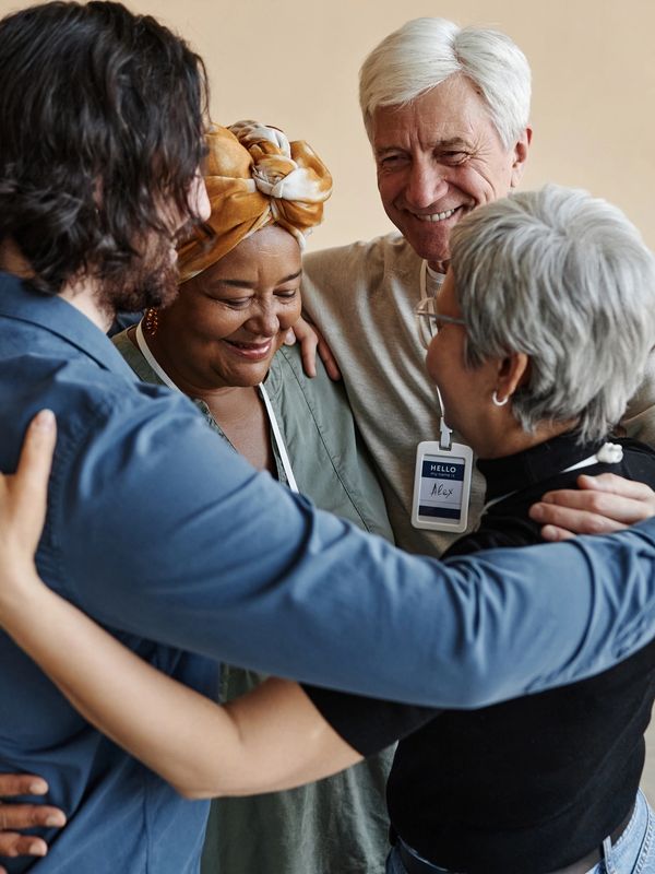 Four diverse people sharing a group hug.