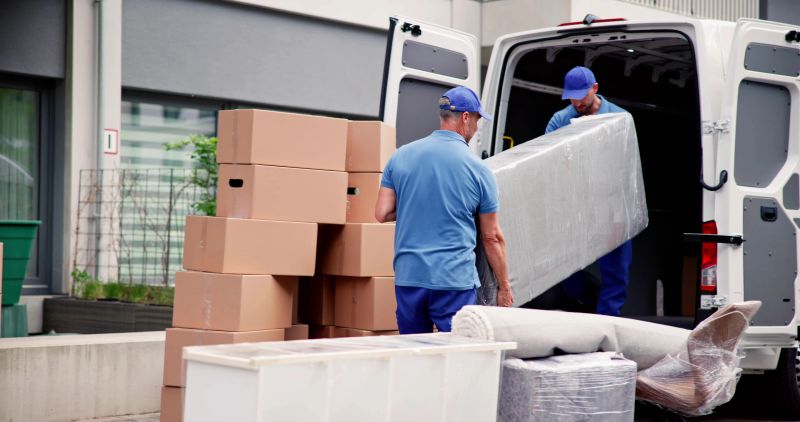 Male Workers In Blue Uniform Unloading Furniture From Truck