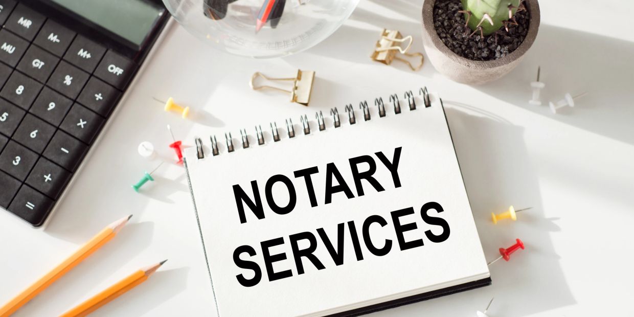 Notebook showing 'Notary Services' with office supplies around.