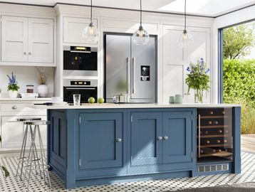 Bright kitchen with blue island, white cabinets, and garden view through sliding doors.
