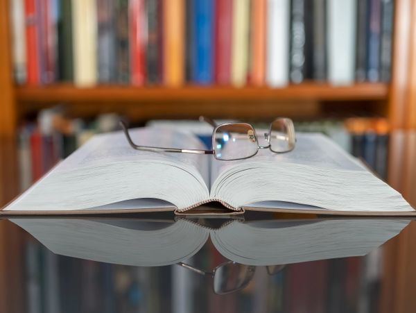Open book with reading glasses resting on it in a library setting. estate planning florida legal solutions probate attorney kentucky