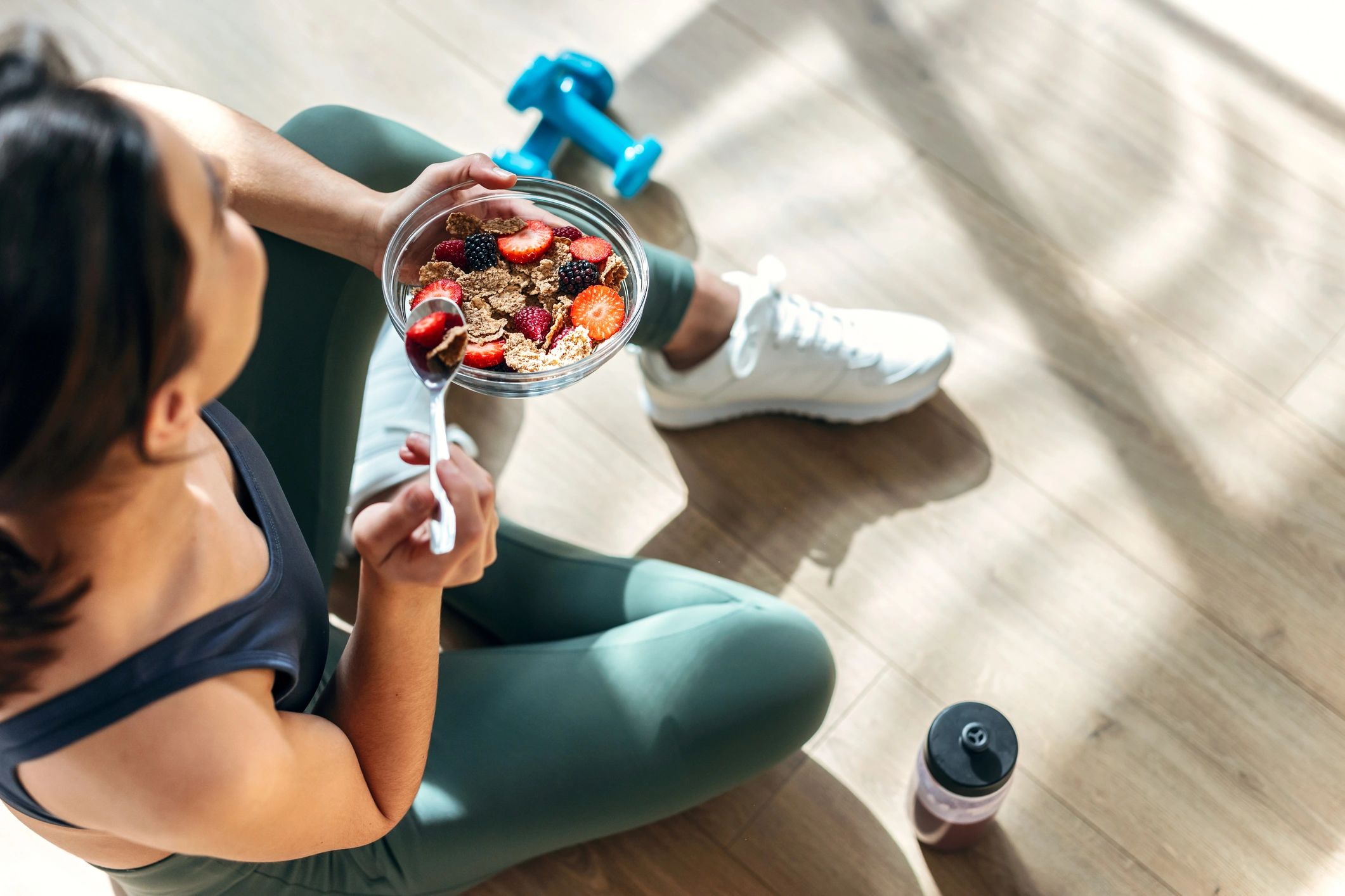 Woman enjoying a healthy bowl of cereal and berries after workout.