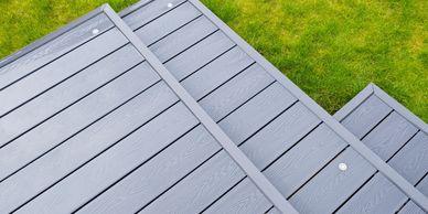Gray composite deck boards with green grass beside.