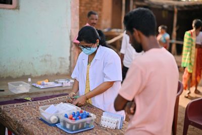 Healthcare worker preparing medical test samples outdoors.