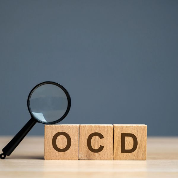 Wooden blocks spelling OCD with a magnifying glass beside them.