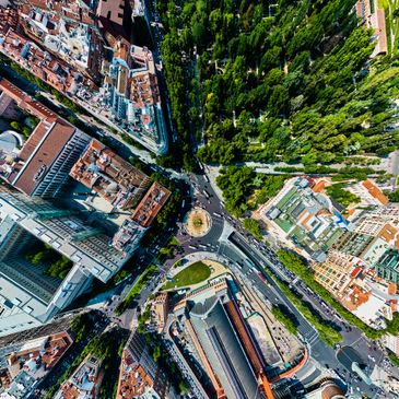 Aerial view of a city with roads, buildings, and a green park area.