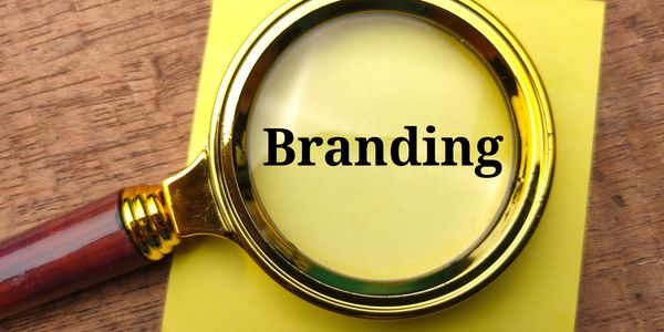 Magnifying glass highlighting the word 'Branding' on a yellow sticky note.