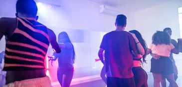 People dancing in a club with colorful lighting and fog effects.