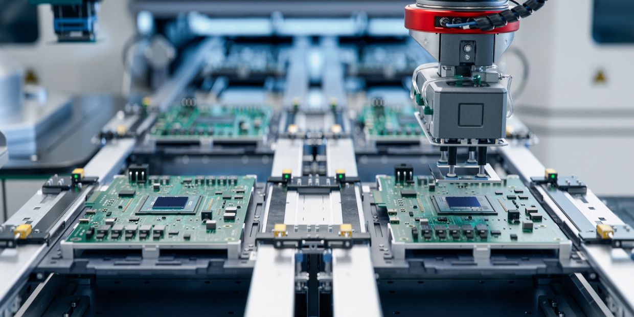 Robotic arm assembling circuit boards on a production line.