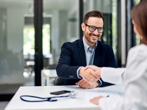 Man shaking hands with a doctor in a modern office.