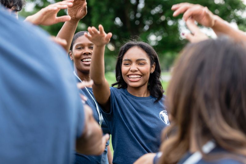 Before getting to work, the diverse team of volunteers raise their arms and cheer in a show of unity.