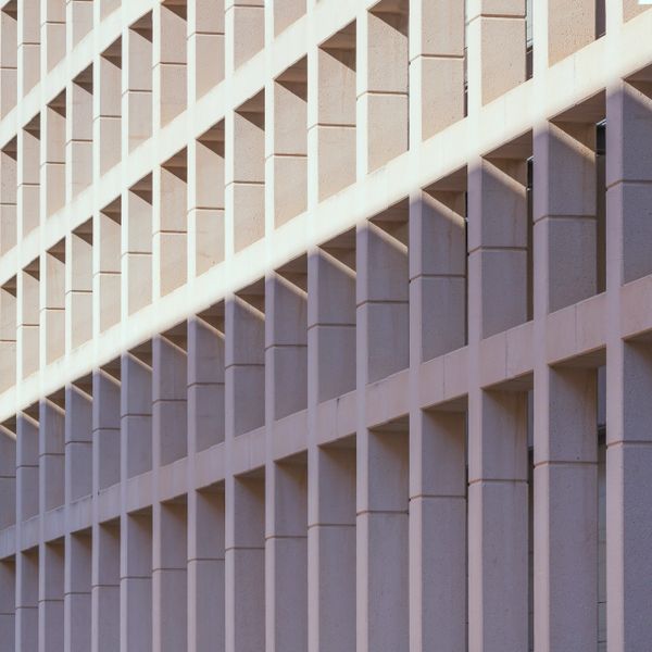 Geometric building facade with repeating square windows and diagonal shadows.