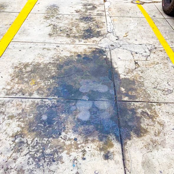 Oil stains and cracks on a parking lot concrete surface.