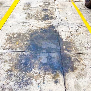 Stained and cracked concrete parking space with yellow lines.