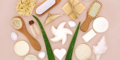 Flat lay of natural spa and skincare items with aloe vera leaves on a pink background.
