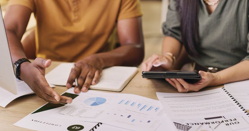 Teamwork, tablet and working on charts, research and documents with data, information or statistics for analysis of business. Paper, graphs and people in meeting with analytics of portfolio and kpi