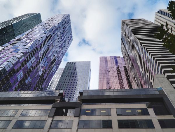 View looking up at tall modern skyscrapers under a blue sky.