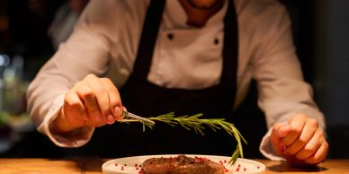 Chef garnishing steak with rosemary.