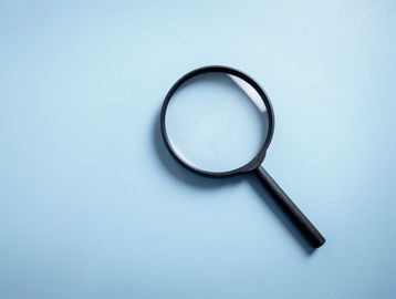Magnifying glass on a blue surface.