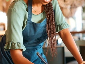 Smiling woman in apron working in a cozy setting.