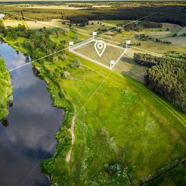 Aerial view of a green landscape with a river and a marked plot of land.
