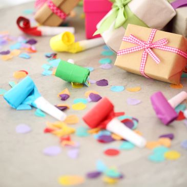 Colorful party blowers and gifts with confetti on a table.
