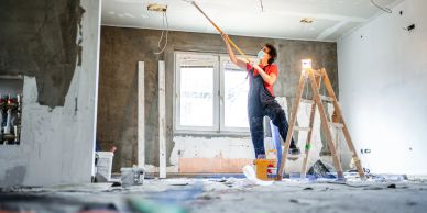 Person painting a ceiling in a room under renovation.