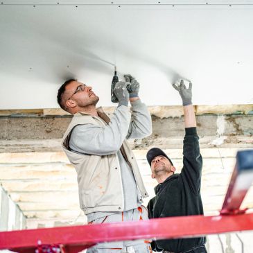 Dos trabajadores instalan un techo interior.