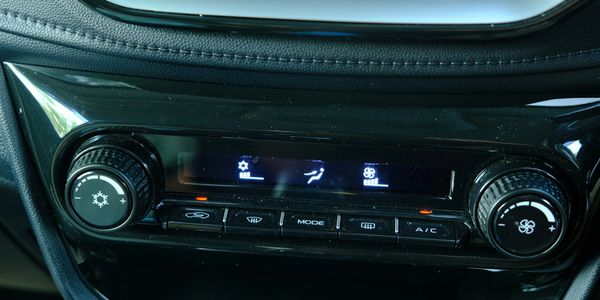Car dashboard climate control panel with knobs and buttons.