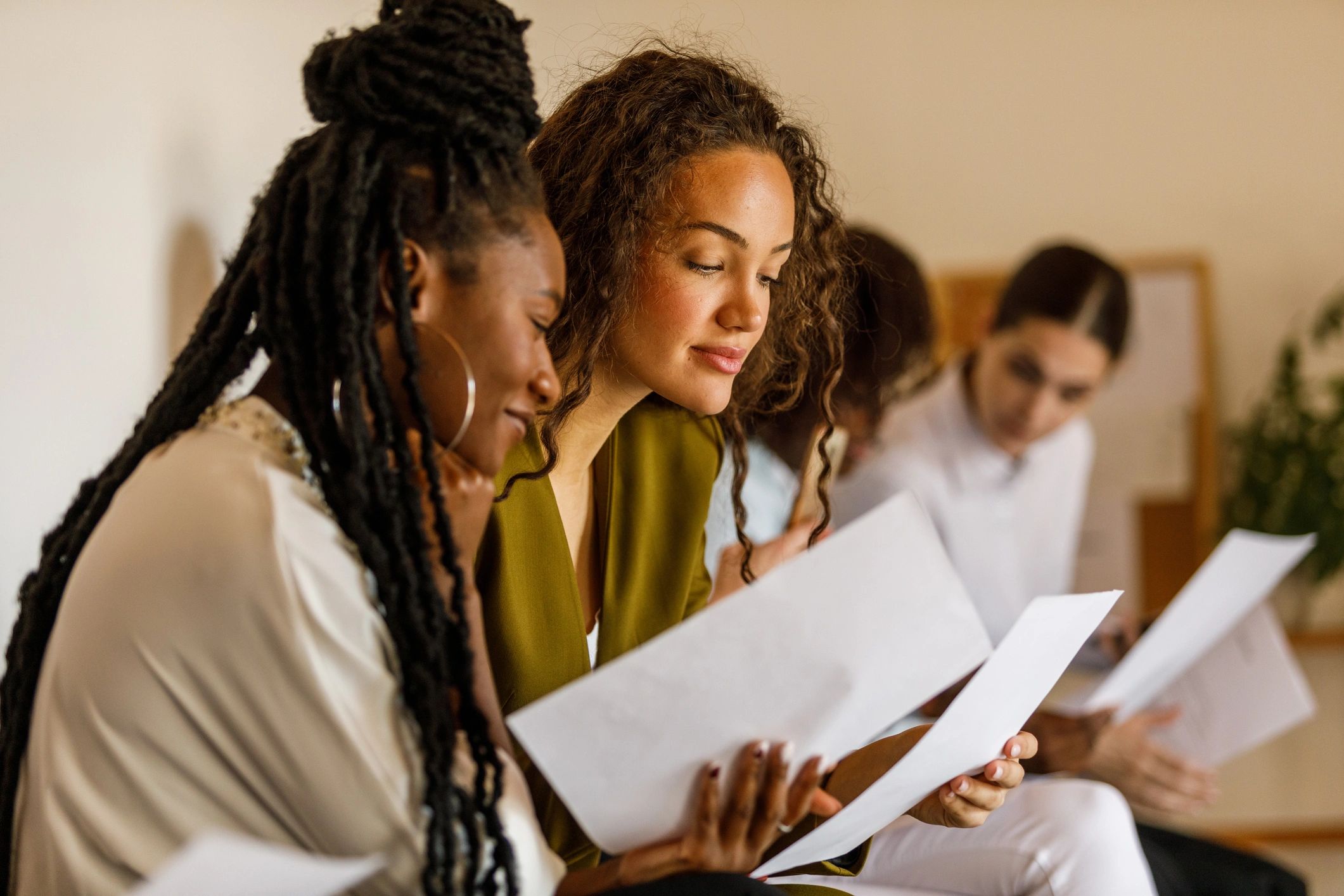 Two women attentively reading documents.