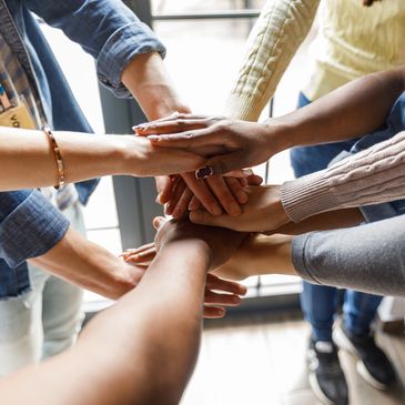 Diverse group of people joining hands in a show of unity.