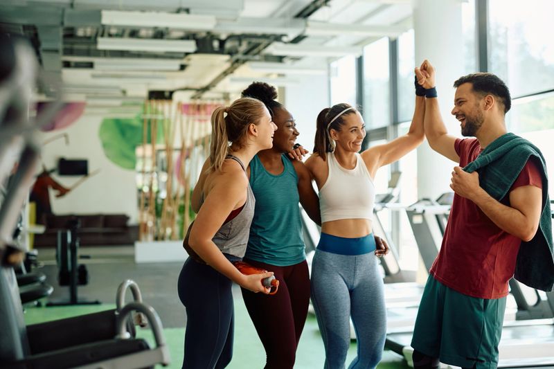 Happy athletic friends congratulating each other on successful sports training in a gym.
