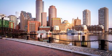 City skyline with waterfront and boats at sunset.
