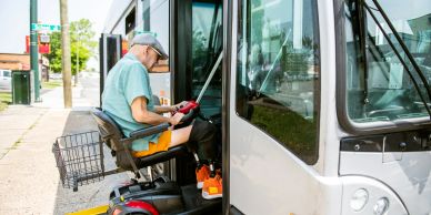 Man in mobility scooter boarding a bus.