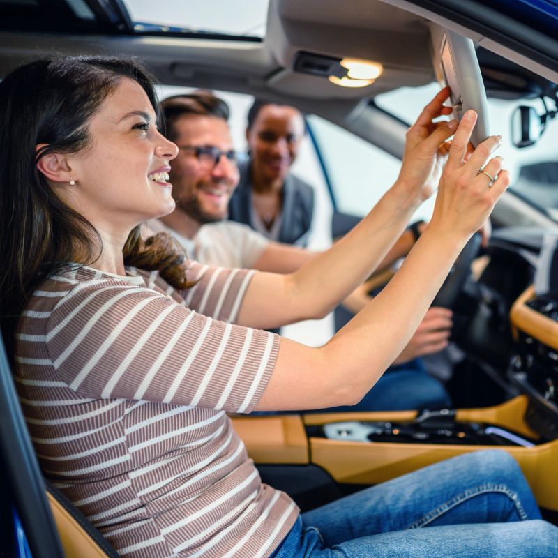 Saleswoman helping the couple customer to choose a new car