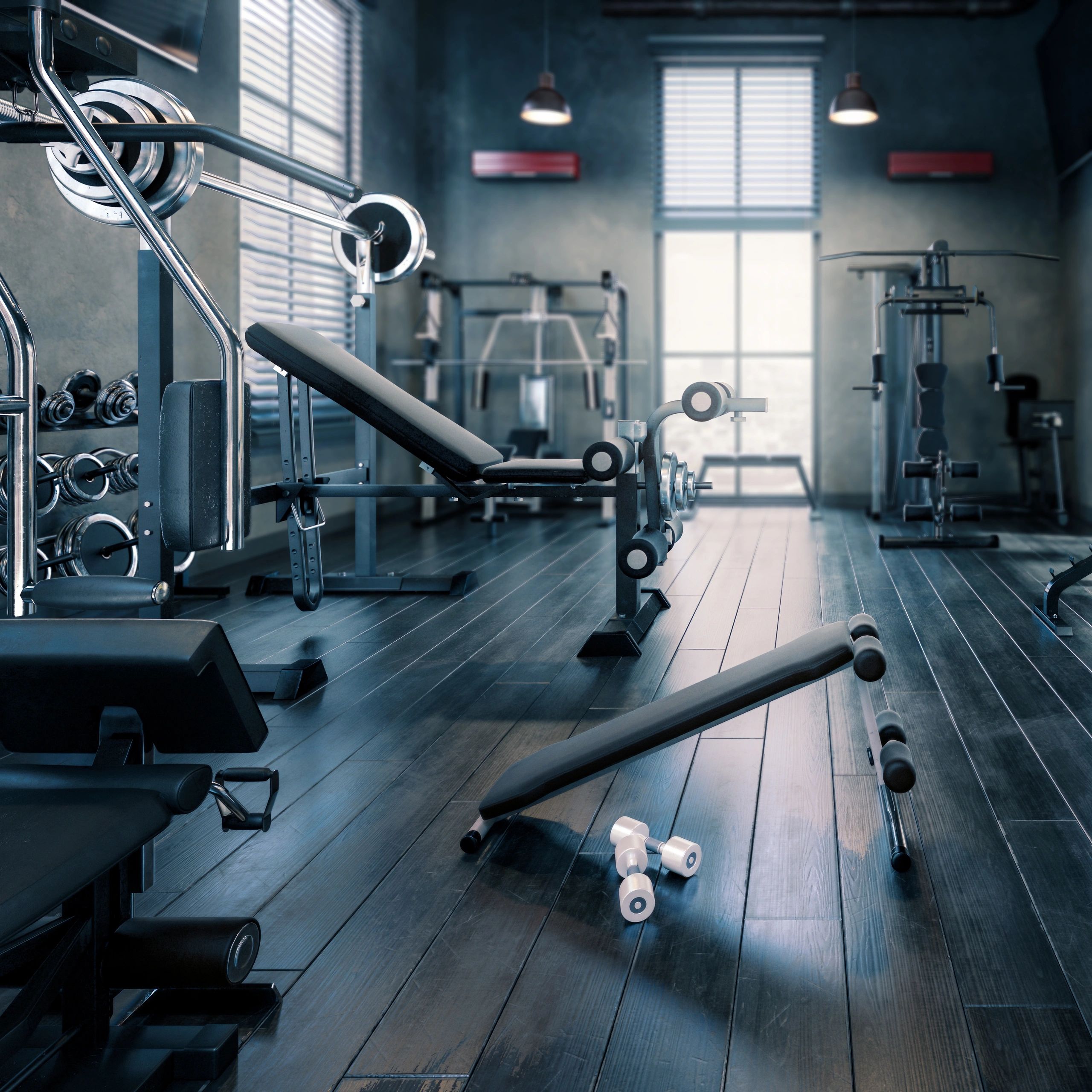 Modern gym with benches, weights, and workout machines in a clean, spacious room.