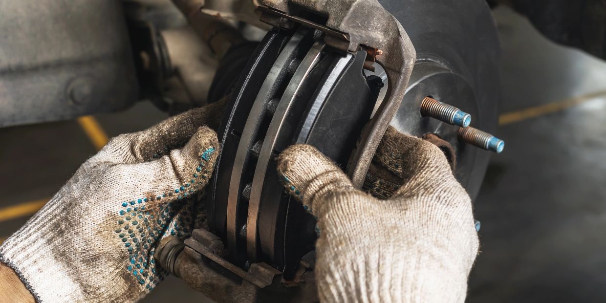 Hands fitting new brake pads on a vehicle.