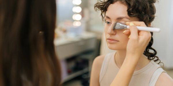 Makeup artist applying foundation on woman's face.