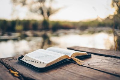 Open book on wooden surface near water.
