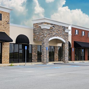 Empty storefronts in a modern shopping plaza on a clear day.