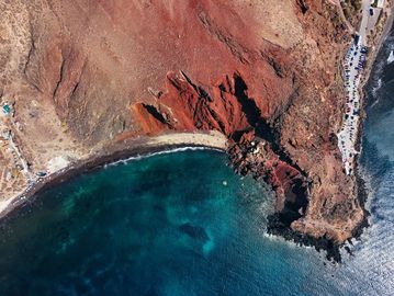 Aerial view of a rocky coastline with clear blue water and a small beach.