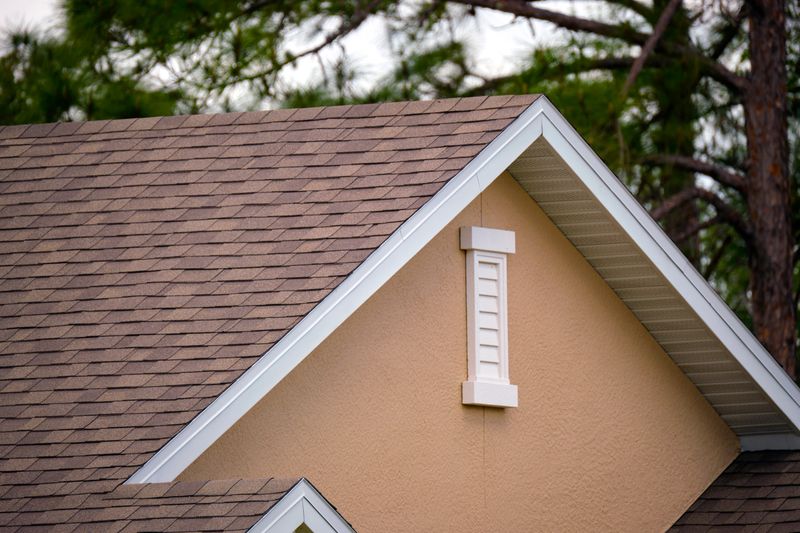 A newly installed shingle roof on a suburban home under a clear blue sky.