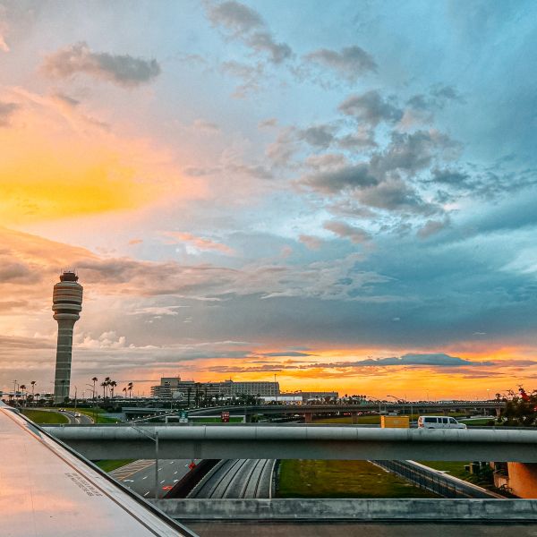 Airport control tower during sunset with colorful sky.