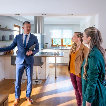 Real estate agent showing a modern kitchen to two women.