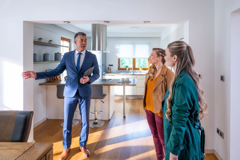 Real estate agent showing lesbian couple modern dining room in apartment